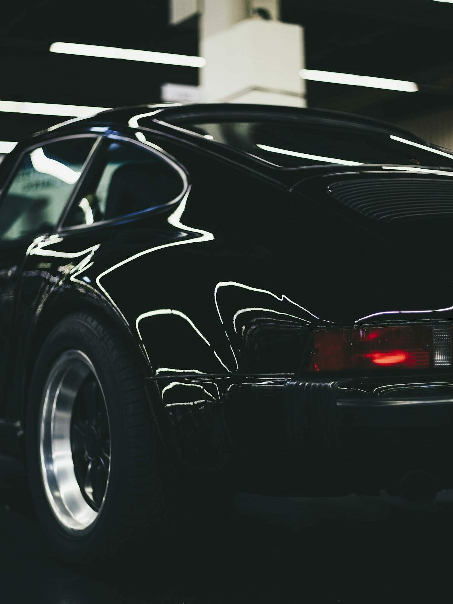 Elegant classic black car with shiny chrome and rear lamp visible in an indoor setting.