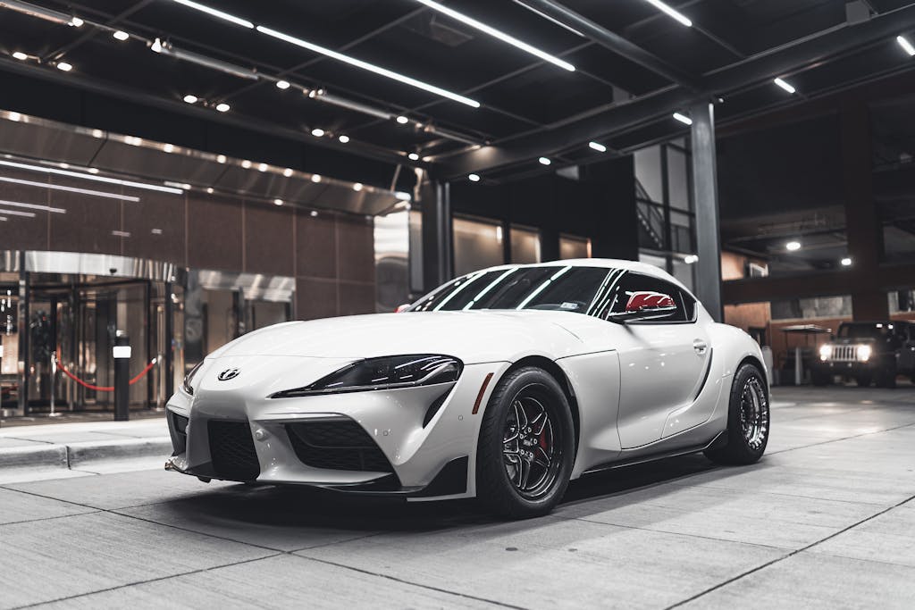 A white sports car displayed indoors, showcasing its design and luxury appeal.