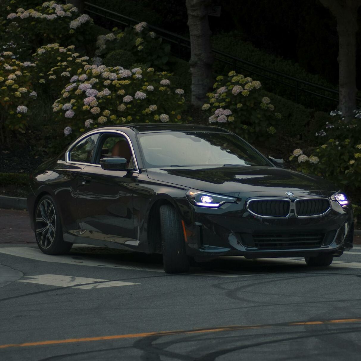 Sleek BMW sports car navigating an urban street at twilight in Los Angeles.